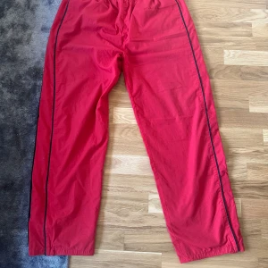 Röda larose techbyxor - Säljer ett par röda techbyxor! Byxorna är lösa och bekväma, perfekta för en avslappnad dag hemma eller lättare träning.  -skick: 8.5/10  - ordinarie pris: 700 -pris kan diskuteras!