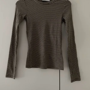 Randig långärmad tröja - Säljer en snygg och bekväm randig långärmad tröja. Den är perfekt för både vardag och lite kyligare dagar. Tröjan är i normal passform och har ett klassiskt randigt mönster i vitt och grått. Materialet känns mjukt och skönt mot huden. Passar perfekt till jeans eller kjol!