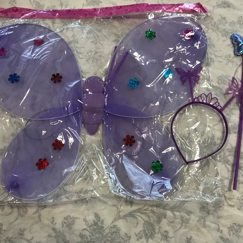 Säljer ett set med fjärilsvingar, diadem och trollstav. Finns i flera färger: lila, rosa, mörkrosa och röd. Vingarna är dekorerade med glittriga blommor och setet är perfekt för fest eller utklädnad. Vingarna är gjorda av plast och diademet har små fjärilar på sig. 75kr/ paket. sammafrakt . Asusteet.