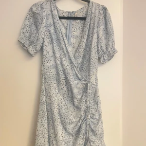 Blå blommig klänning - Kort blå klänning från Nelly.  Storlek 36. 