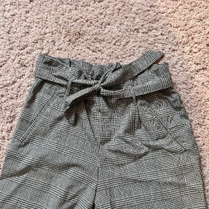 Grå Kostymbyxa  - Stiliga kostymbyxor i grå rutigt! Skitsnygga till en vanilj t-shirt eller matchande kavaj.  Används inte längre för dem är för små för mig.