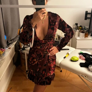 Magisk klänning - Magisk klänning i vinröd färg med svarta detaljer. Detaljerna är i mocka-liknande material. Armarna är delvis genomskinliga. Klänningen är köpt på missguided och är helt oanvänd. Lappar osv är fortfarande på, säljer då jag inte fått tillfälle att använda.