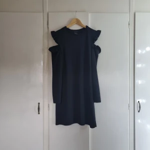 Svart klänning - Klänning med volang och "hål" vid överarmarna. 