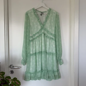 Klänning - Fin sommarklänning i grönt tyg och ljusa vita blommor! V-ringning, volanger och tunna ärmar vilket är skönt på sommaren