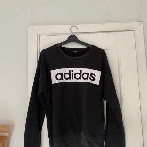 Köp två så bjuder jag på frakten!! En svart långärmad tröja från Adidas med en vit logotyp på bröstet. Tröjan är en del av Adidas Sport Essentials-kollektion och är tillverkad med Climalite-material för att hålla dig torr och bekväm.