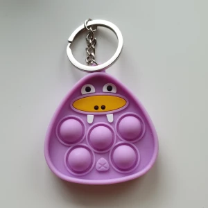 Lila valros pop-it, fidget toys, nyckelring, ny  - Pop-it/fidget toys nyckelring Färg: lila  Form: valros  Skick: oanvända. Ej lämpliga för barn under 3år. Då det innehåller smådelar