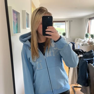 Ljusblå hoodie med strasstenar från Vonstudio - Säljer en ljusblå hoodie från Vonstudio i storlek S.  Dekorerad med strasstenar i text och en ängel på bröstet, några stenar\paljetter har lossnat men det är inget man tänker på🙌🏻 Annars väldigt fin i övrigt. Säljer då jag inte använder den.🩵