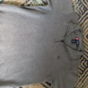 Grå tröja med dragkedja från Chaps - Säljer en stilren grå tröja från Chaps med halv dragkedja och liten broderad logga på bröstet. Perfekt för lager-på-lager och passar till det mesta. Mjuk och bekväm med klassisk passform.