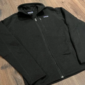 Svart fleecejacka från Patagonia - Svart fleecejacka från Patagonia med hel dragkedja framtill och hög krage. Jackan har en bröstficka med dragkedja och är långärmad. Perfekt för lager-på-lager och svalare dagar. Super bekväm och riktigt snygg. Tveka inte på att ställa frågor👍🏻Tröjan är använd extremt fåtal gånger och har inga defekter.