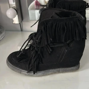 Svarta fransskor  - Passar även 37!Säljer ett par svarta sneakers med snörning och coola fransdetaljer runt skaftet. Skorna har en diskret kilklack som ger lite extra höjd och en sportig känsla. Perfekta för dig som vill sticka ut med din stil
