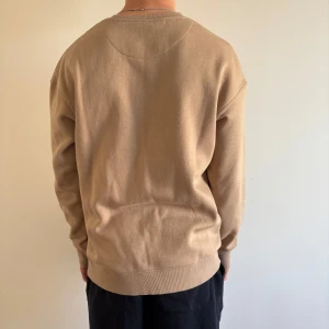 Beige sweatshirt i bomull - Säljer en stilren beige sweatshirt i mjuk bomull. Tröjan har rund halsringning och långa ärmar med ribbade muddar vid ärmslut och nederkant. Perfekt för en avslappnad och enkel look. Skriv kring mer information😀!