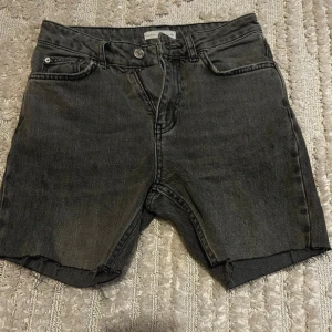 Svarta jeansshorts från Perfect Jeans - Snygga svarta jeansshorts från Perfect Jeans med råa kanter och klassisk femficksdesign. Perfekta för en avslappnad stil och passar till det mesta. Stängs med knapp och dragkedja.