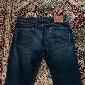 Levi's 505 mörkblå jeans - Klassiska mörkblå Levi's 505 jeans med raka ben och femficksdesign. Byxorna har normal passform och är tillverkade i slitstarkt denim. Perfekta för dig som gillar tidlös stil och vill ha ett par jeans som funkar till det mesta.