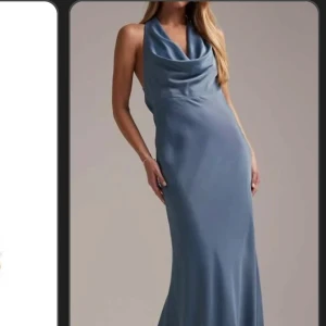 Blå långklänning med draperad hals - Säljer en elegant blå långklänning med draperad halsringning och ärmlös design. Klänningen har en smickrande, figurnära passform och är tillverkad i ett mjukt, glansigt material som ger en lyxig känsla.