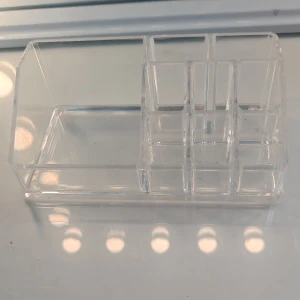  sminkorganiserare  - Praktisk och stilren sminkorganiserare i genomskinlig akryl med flera fack i olika storlekar. Perfekt för att förvara sminkborstar, läppstift, ögonpennor och andra sminkaccessoarer. Enkel att hålla ren och passar snyggt på sminkbordet.