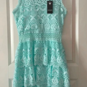 Mintgrön spetsklänning från Guess - Superfin mintgrön klänning från Guess med vackra spetsdetaljer. Ärmlös modell med rund halsringning och markerad midja. Perfekt för sommarens tillfällen!