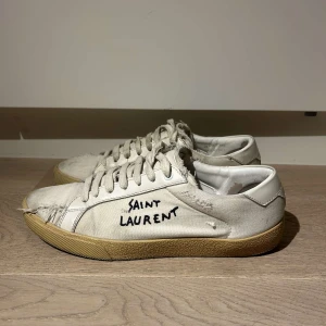 Vita Saint Laurent sneakers - Säljer ett par vita sneakers från Saint Laurent. Storlek 41.5 är i bra skick skriv vid någon fundering!