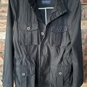 Svart jacka från McNeal med fickor - Svart jacka från McNeal med fyra stora fickor framtill och knappar. Jackan har dragkedja och knappstängning samt hög krage. Perfekt för dig som vill ha en stilren och funktionell jacka. Den är i storlek M skriv om ni har några funderingar!