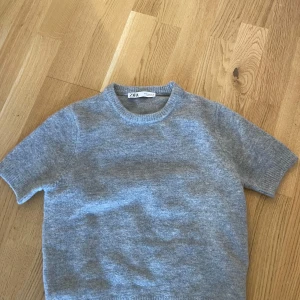 Grå stickad kortärmad tröja från Zara - Mysig grå stickad tröja från Zara med rund halsringning och korta ärmar. Nästan helt oanvänd! 