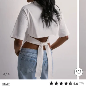 Vit croppad topp med knyt från Nelly - Säljer en vit croppad topp från Nelly med korta ärmar och snygg knytning i ryggen. Toppen har en enkel och stilren design som passar perfekt till jeans eller kjol.
