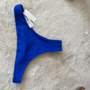 Blå cheekini   - Säljer en snygg blå bikiniunderdel. Stringmodell / cheekini. Perfekt för strand eller poolhäng. Enkel och stilren modell utan extra detaljer.