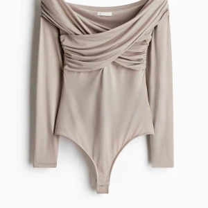 Beige omlott-body med drapering från Zara - Endast testad. Säljer en beige body från H&M med snygg omlott framtill. mjukt stretchigt material.  pris kan diskuteras 🥰