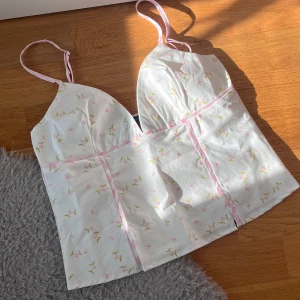 Ny blommig topp med rosa detaljer - Super sött linne från asos! I helt nytt skick, har endast blivit testad. Super gulligt blommigt tyg med detaljer i rosa gingham 🩷