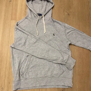 Grå Ralph Lauren Hoodie - Säljer en klassisk grå hoodie från Polo Ralph Lauren med broderad logga på bröstet. Perfekt för en avslappnad stil. Vid fler frågor kom privat💯