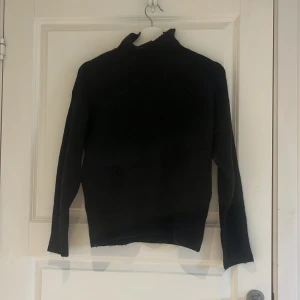 Svart stickad polotröja från BikBok - Säljer en svart stickad polotröja från BikBok i ullblandning. Tröjan har lång ärm och hög krage, perfekt för kyliga dagar. Enkel och stilren modell som passar till det mesta.