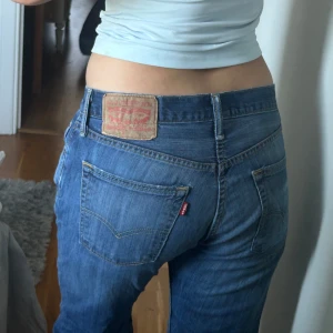 Levis 501 blå jeans - Säljer ett par klassiska blå Levis 501 jeans med raka ben och låg midja. Jeansen har fem fickor, knappgylf och den ikoniska Levis-lappen bak. Perfekta för en avslappnad och tidlös stil.