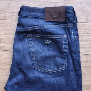 Armani Jeans, 30 rak modell  - Snygga original mörkblå jeans från Armani Jeans med klassisk femficksdesign och logga på bakfickan samt läderpatch i midjan. Stilren tvätt, modell J75 rak modell. Långa ben. Normal midja. Storlek 30, i mycket fint skick, sparsamt använda. Hämtas i Huskvarna vid överenskommelse eller skickas.