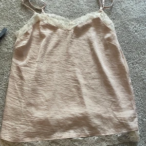 Ljusrosa linnetopp med spets från Ellos - Säljer en ljusrosa linnetopp från Ellos med tunna axelband och vacker spetsdetalj vid halsringning och nederkant. Perfekt för sommardagar eller som ett lager under en kofta. Superfin och feminin look!