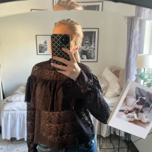 Svart spetsblus med volang från Kappahl  - Säljer en trendig  svart blus i spets med volangdetalj från Kappahl. Använd en gång, inga defekter! 