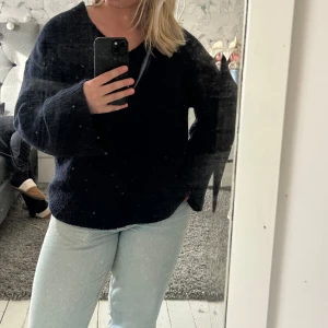 Mörkblå stickad v-ringad tröja från Gina Tricot - Mysig mörkblå stickad tröja från Gina Tricot med v-ringning och breda muddar. Perfekt för lager-på-lager och enkel att styla till jeans eller kjol. Klassisk modell med lång ärm och avslappnad passform.