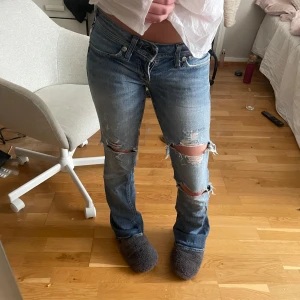 Blå bootcut jeans - Säljer ett par blå bootcut jeans med hål på knänna, på sista bilden ser ni även två hål där bak, skriv om ni har frågor!!💕