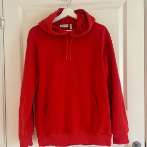Röd hoodie från Weekday - Säljer en klassisk röd hoodie från Weekday med huva och dragsko. Tröjan har en stor magficka och ribbade muddar vid ärmslut och nederkant. Perfekt för en avslappnad stil eller myskvällar. PRIS GÅR ATT DISKUTERAS 