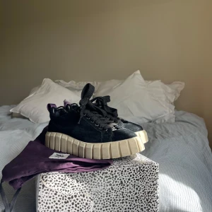 Svarta Eytys - Säljer ett par svarta sneakers från Eytys. Använda ett fåtal gånger men det lila snöret baktill är uppgnavt av hund på ena skon. (Inget som syns när byxan går över skon). Annars i väldigt bra skick. Kommer med originalkartong och tygpåse.