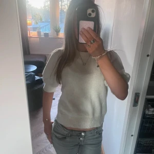 Vit stickad kortärmad tröja - Säljer en söt vit stickad tröja med korta puffärmar och ribbad nederkant. Perfekt till jeans eller kjol för en fräsch look. Tröjan har en mjuk och bekväm känsla och passar till många tillfällen.