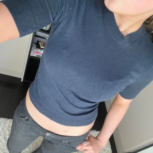 Mörkblå croppad tröja från 157 - Säljer en mörkblå croppad tröja från 157 med korta ärmar och rund halsringning. Tröjan är i ett mjukt, stickat material och passar perfekt till jeans eller kjol. Enkel och stilren design som är lätt att matcha.