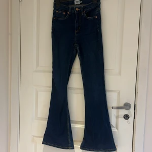 Snake Flare jeans - Mörkblå jeans från lager med hög midja och klassisk bootcut-passform. Jeansen har orange sömmar och fem fickor. Perfekta för dig som gillar en retrostil med utsvängda ben. XS short
