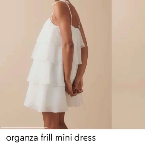 Vit volangklänning - Superfin kort klänning i offwhite organza med flera lager volanger och tunna axelband. Lätt och luftig känsla, perfekt för varma dagar. Snygg och trendig. Aldrig använd, köptes förra året med prislappar kvar