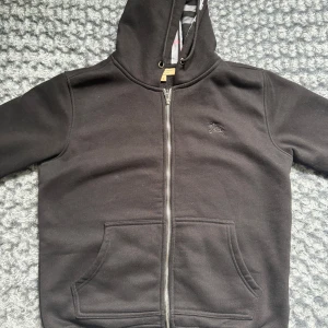 Svart burberry zip - Svart Burberry hoodie i storlek M. Använd få gånger, inga fel eller fläckar. Sitter bra och ser clean ut. Enkel, stilren och passar till det mesta.