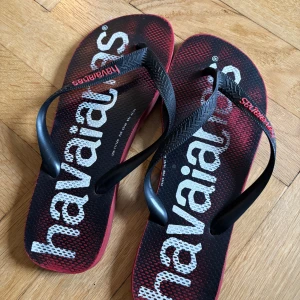 Svarta och röda Havaianas  - Snygga flip-flops från Havaianas i svart och rött med stor vit logga på sulan. 
