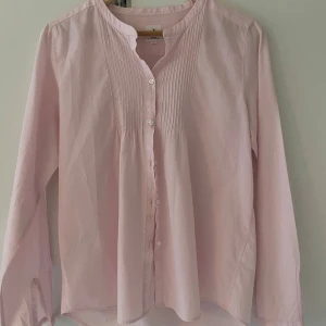 Ljusrosa skjorta från Boomerang - Säljer en ljusrosa skjorta från Boomerang i klassisk modell med knappar framtill och fina veckade detaljer vid bröstet. Den är nästan helt oanvänd och i jättebra kvalite 💕💕