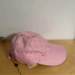 Rosa Gucci keps med monogram - Snygg rosa keps från Gucci. Justerbar rem bak och böjd skärm. Tillverkad i bomull och polyester, perfekt för dig som vill sticka ut med en lyxig och trendig accessoar. Tveka inte på att höra av er vid frågor. *Aldrig använt*