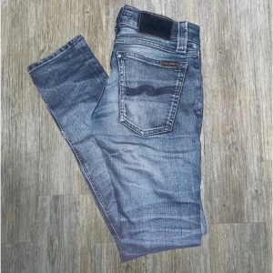 Blå jeansbyxor från Nudie Jeans - Säljer ett par klassiska blå jeansbyxor från Nudie Jeans med slitningar. Jeansen är i mycket bra skick och är i slim fit ( sista bilden ) Passar bra på någon som är runt 156. De är i storleken W24 och L30. Hör av dig direkt vid frågor eller liknande!🙂🙌