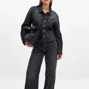 Mörkgrå/svart jeansjacka med knappar - Snygg svart jeansjacka från Na-kd med silverfärgade knappar framtill. Jackan har lång ärm och något croppad passform. Använd ca 4 ggr, skicka privat för fler bilder😇