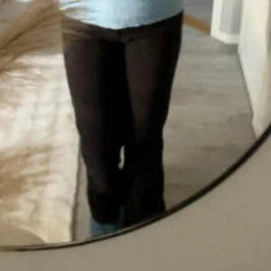 Svarta kostymbyxor med fickor bak - Säljer ett par svarta byxor med utsvängda ben och snygga fickor med lock bak. Byxorna har en klassisk look och passar perfekt till en chill vardagsstil. Materialet känns mjukt och bekvämt, och de har en normal passform i midjan.