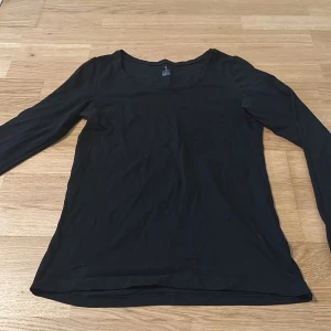 Svart långärmad topp från ouBest - En basic svart långärmad topp från ouBest i mjuk bomull. Enkel och stilren design med rund halsringning, perfekt att matcha med jeans eller kjol. Sitter skönt och har en normal passform.