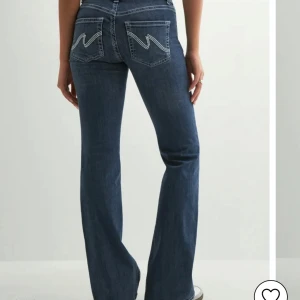 Blå bootcut jeans med broderade fickor - Snygga blå bootcut jeans med coola broderade detaljer på bakfickorna. Jeansen har låg midja, klassisk femficksdesign och är tillverkade i mjukt denimtyg. Perfekta för dig som gillar en avslappnad men trendig look. De är lite slitna mer till!! (Skriv för bild) 